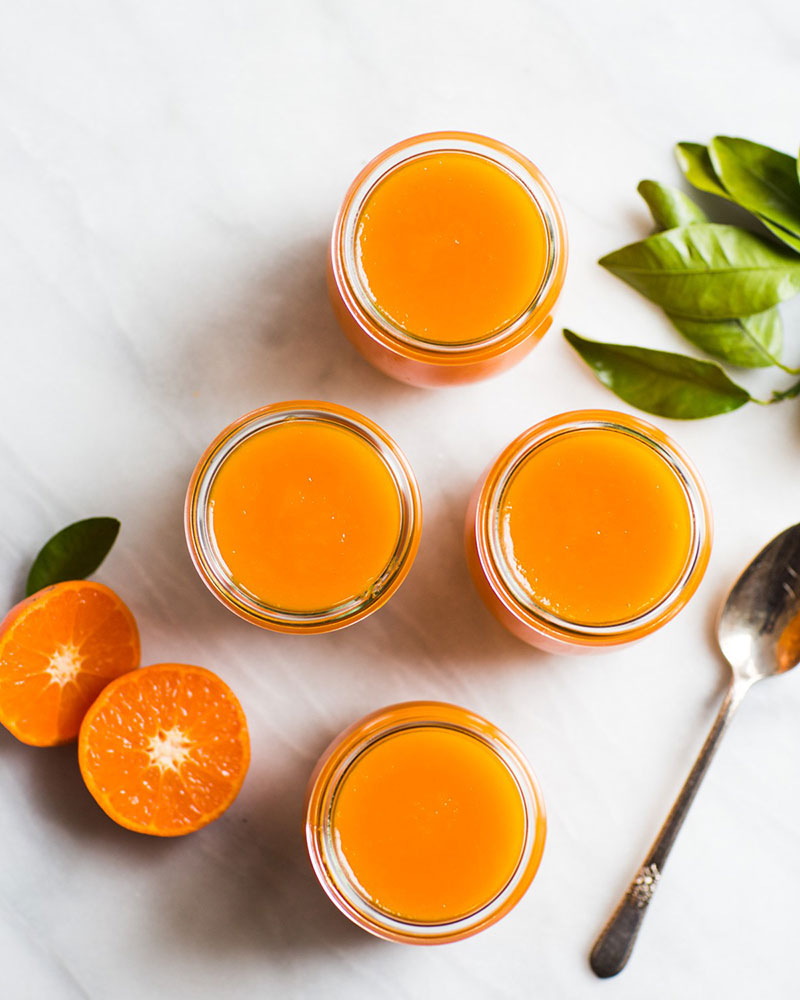 Bottles of orange jam surrounded with orange slices