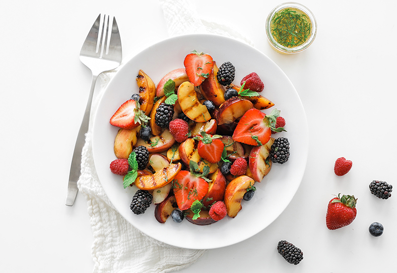 Bowl of grilled stone fruit, strawberries, raspberries, blueberries and black berries.