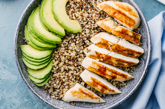 Bowl with quinoa topped with avocado and grilled chicken.