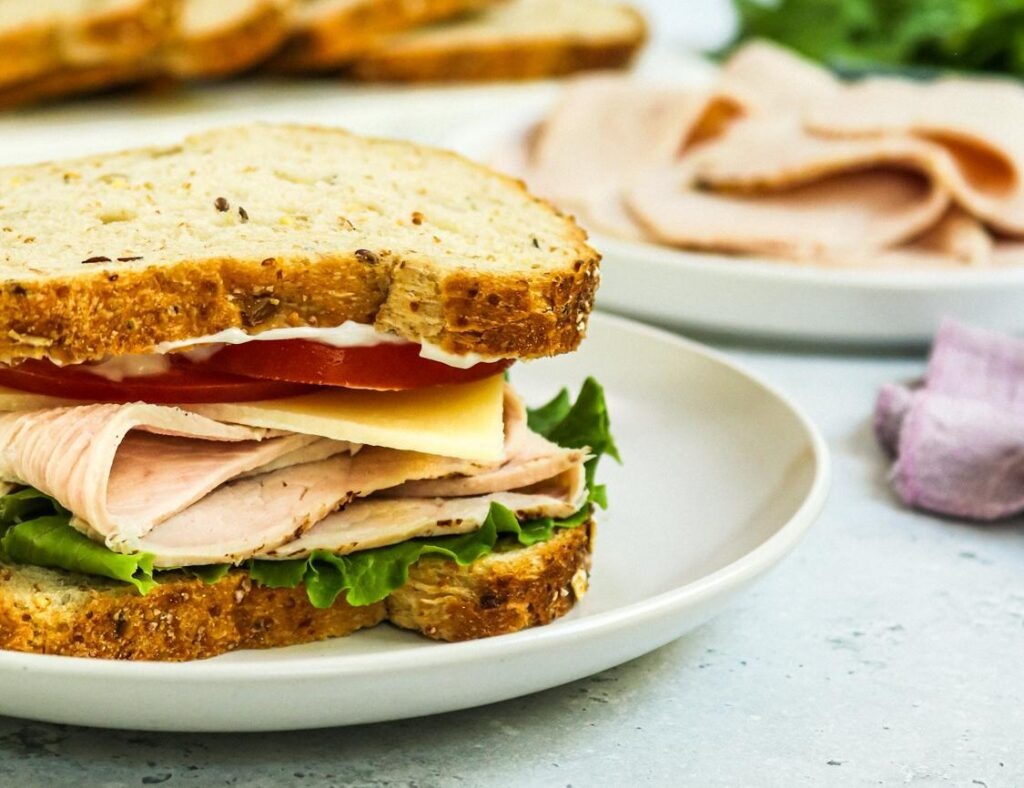 2 brothers turkey being used on a sandwich served on a white plate