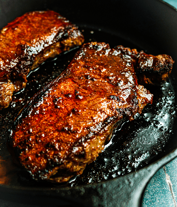 Two Steaks Being Cooked in a Cast Iron Skillet