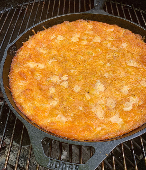 Cast iron skillet with smoked crab dip topped with melted cheddar cheese.