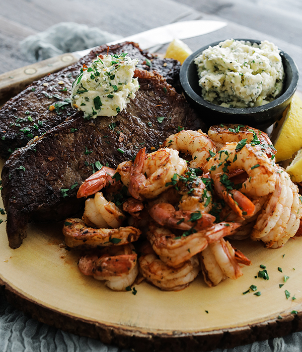Steak and shrimp served on a plate with herb butter.