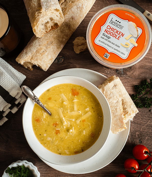 Heinen's Chicken Noodle Refrigerated Soup, plated with a side of bread