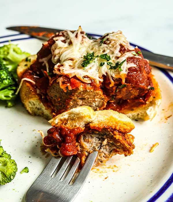 Open-Faced Meatball Sandwich on a plate with a side of broccoli. 