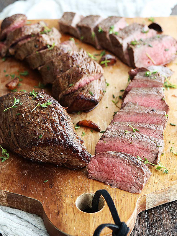 Medium-rare steaks sliced on a cutting board.