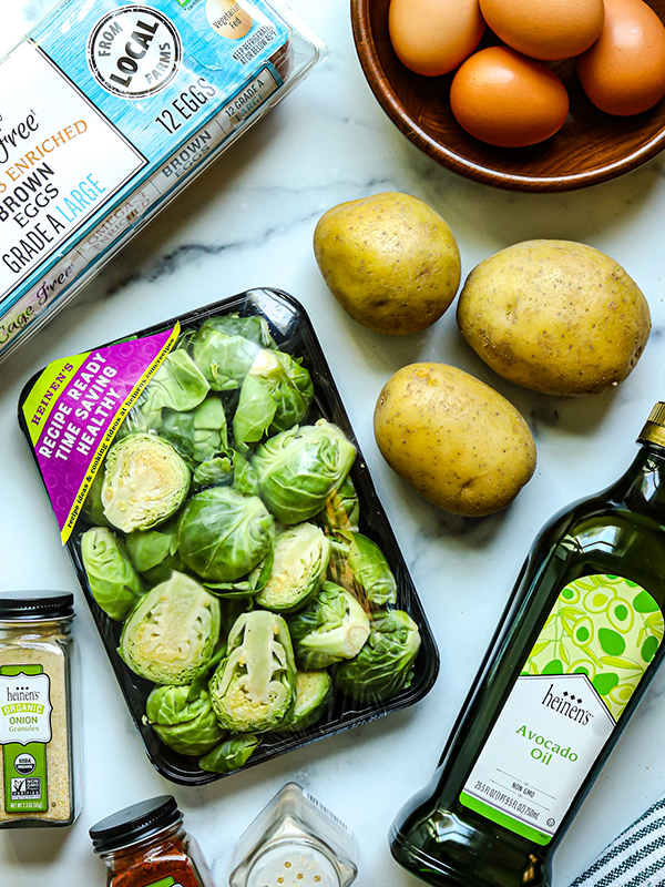 Sliced brussels sprouts next to potatoes, eggs, avocado oil and spices.