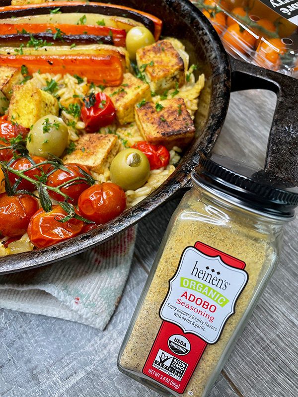 Vegetarian paella in a cast iron skillet next to adobo seasoning.