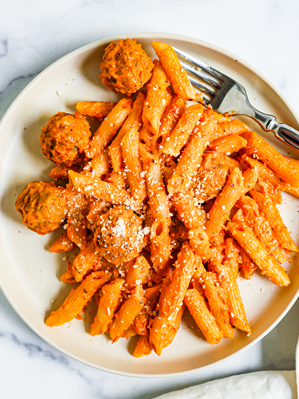 Penne pasta with red sauce and meatballs, topped with parmesan cheese.