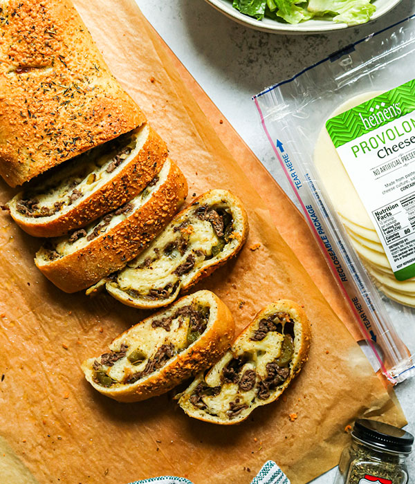 Cheesesteak Stromboli on a Cutting Board with Heinen's Provolone Cheese and Salad