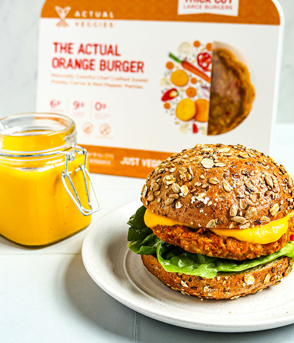 Actual Veggies Veggie Burger on a Bun with Lettuce and Sauce Beside a Jar of Sauce and Actual Veggies Packaging