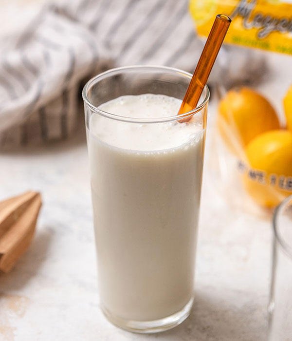 Frosted Lemonade in a glass with straw. Meyer lemons in the background.