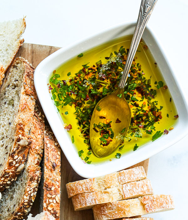 Extra Virgin Olive Oil in a Serving Bowl with a Fresh Herbs and Bread