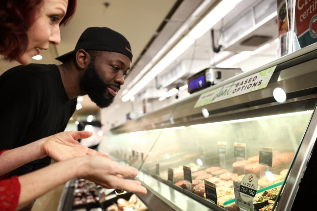 A man and a woman looking at plant-based meat options at a meat counter.