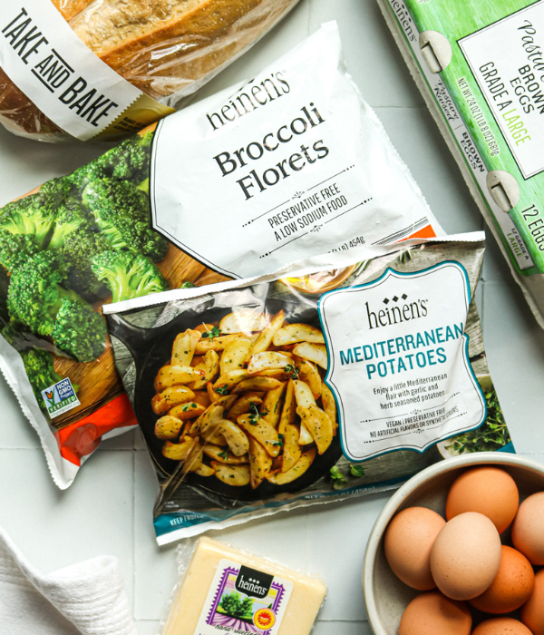 Heinen's Take and Bake bread, Frozen Broccoli Florets, Frozen Mediterranean Potatoes, Carton of pasture Raised brown eggs on counter.