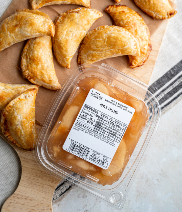 Heinen's Apple Pie Filling on wooden serving block with Apple Hand pies surrounding It.