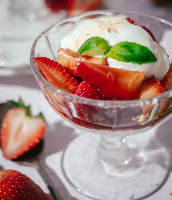 A close up of a Balsamic Strawberries & Cream dessert in a clear glass serving bowl.