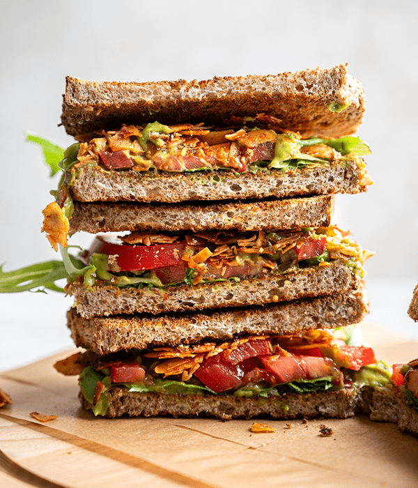 Three Sliced BLT Sandwiches with Crispy Coconut Bacon Stacked Vertically