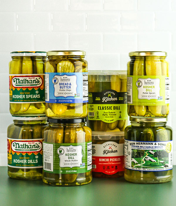 Vertical Photo of Eight Packages of Gourmet Deli Pickles Stacked in Two Rows in front of a White Background