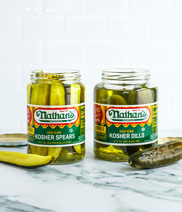 Two Open Jars of Nathan's Pickles with a Whole Pickle and Two Pickle Spears Sitting Beside the Jars