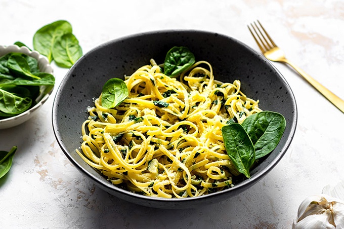 Linguine noodles with spinach and parmesan cheese in a bowl.