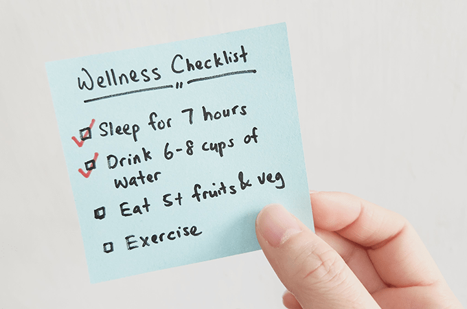 A Light Blue Sticky Note Titled Wellness Checklist with Four Tasks Below