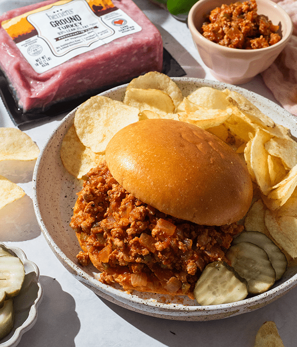 A Sloppy Joe Sandwich on a Plate Beside Kettle Chips
