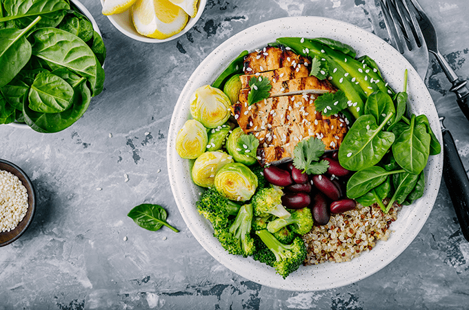A Large Grain Bowl with Sliced Chicken and Green Vegetables