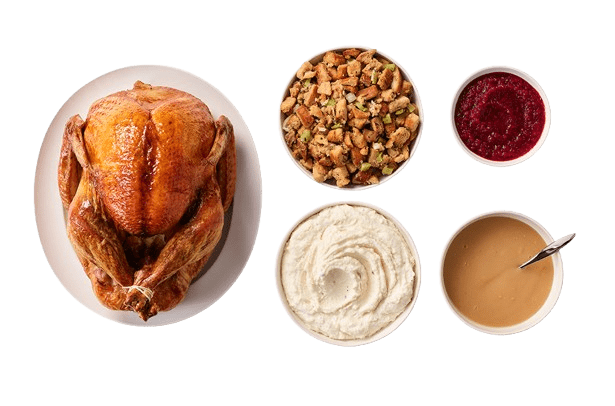 A Whole Cooked Turkey on a Plate with a Bowl of Stuffing, a Bowl of Mashed Potatoes, a Bowl of Gravy, and a Bowl of Cranberry Relish