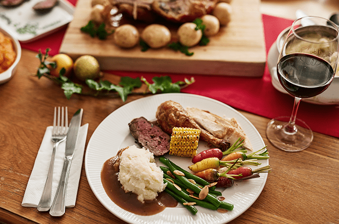 A Plate with a SMall Portion of Meat and Veggies on a Holiday Tablescape with a Glass of Wine