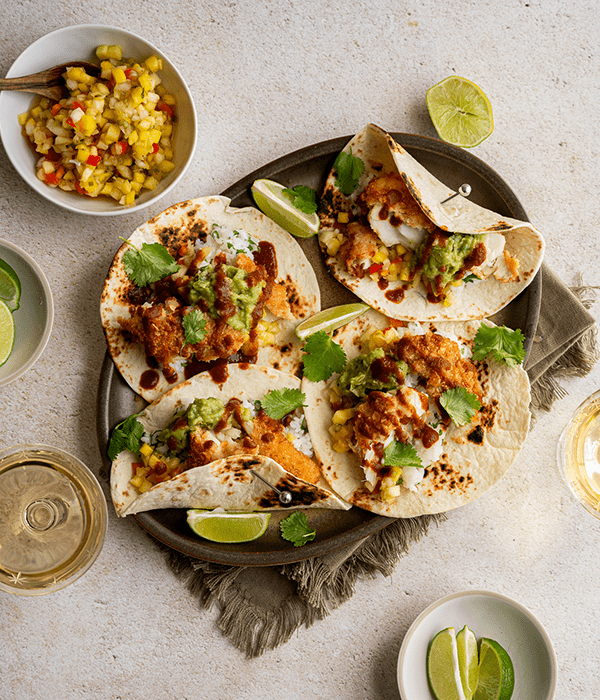 Four Parmesan Crusted Cod Tacos on a Serving Platter Beside a Bowl of Pineapple Mango Salsa