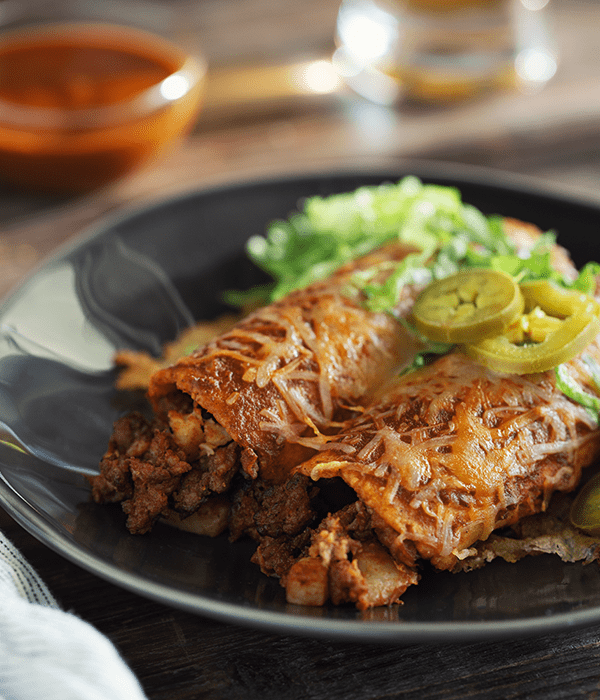 Chorizo and Potato enchilada being served on a plate with garnishes