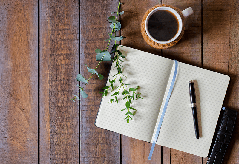 A journal with a pen and some tea
