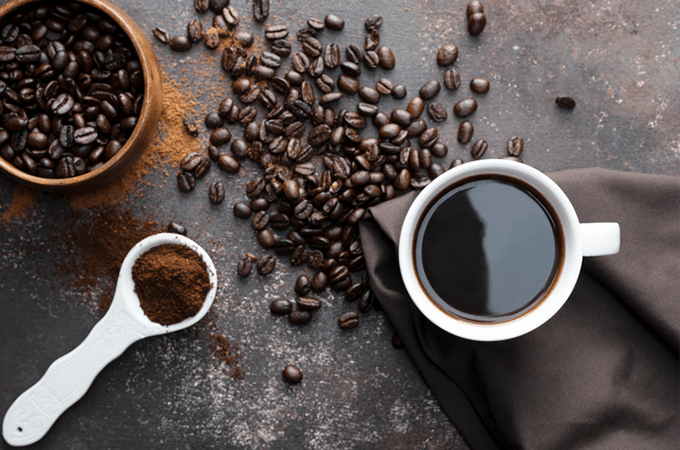 a cup of coffee surrounded by coffee beans 