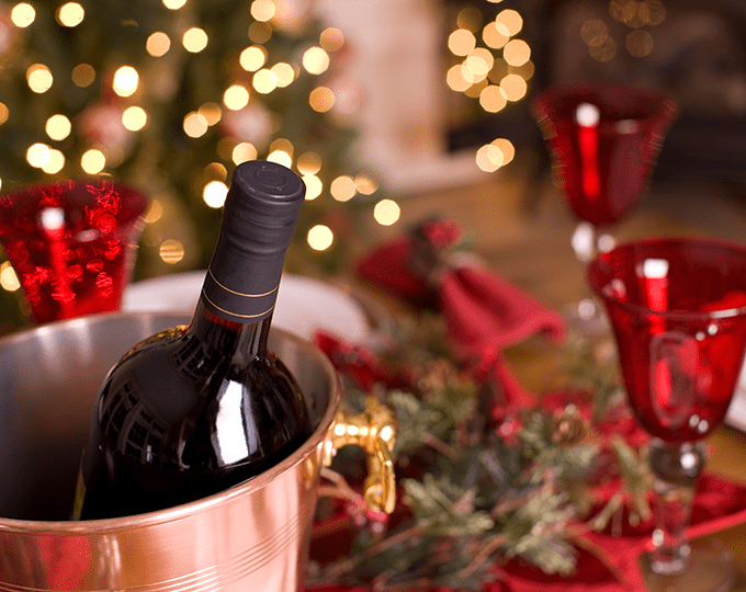 A Red Wine Bottle in an Ice Bucket Beside a Holiday Table