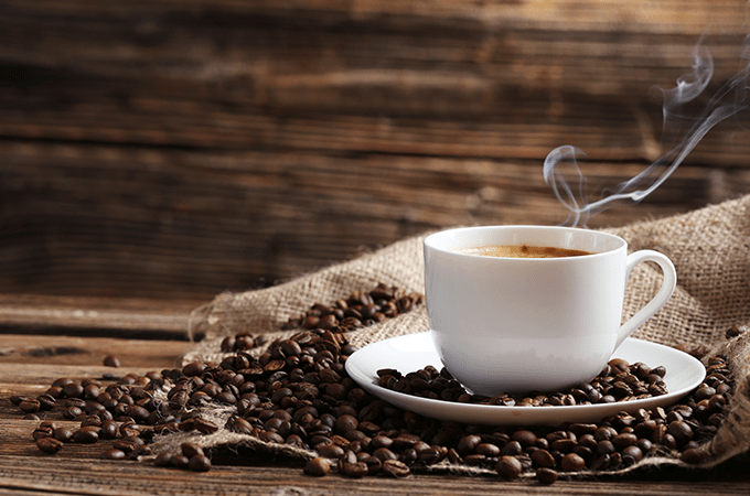 A steaming cup of coffee sitting on a plate