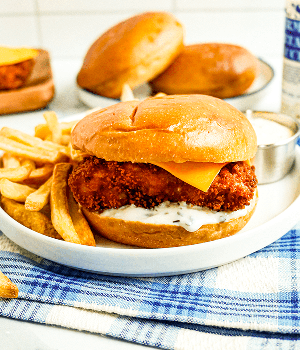 Copycat Fried Fish Sandwich, plated with a side of French fries and sauce