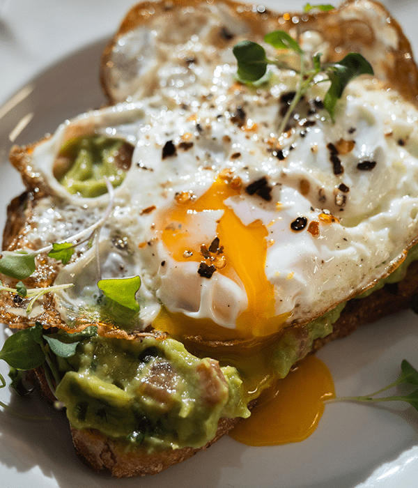 The Fried Egg and Guacamole Toast plated with garnishes, ready to be eaten.