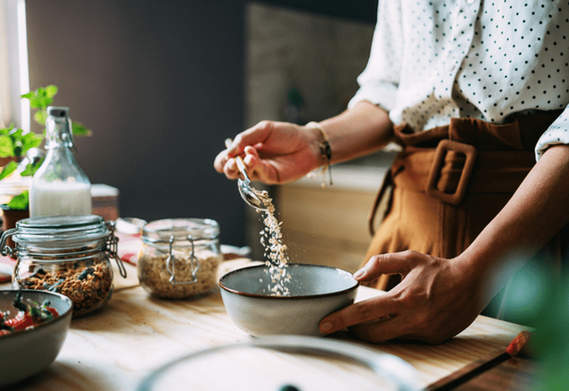 someone pouring fibrous oats into a bowl