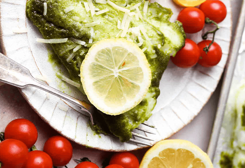 Kale Pesto with Roasted Cod plated with some tomatoes and lemon slices