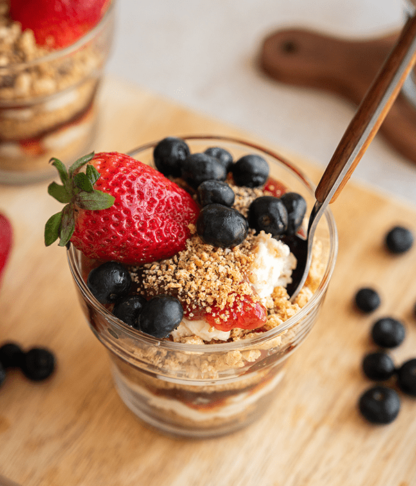 Mascarpone Parfait topped with fresh blueberries and strawberries, with a spoon dipped in