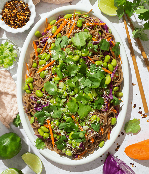 Yoko's kitchen Cold Soba Noodle Salad plated next to some crushed red pepper, green onion, and lime