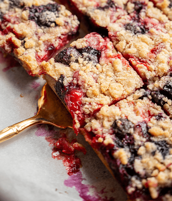 a close up look at the Berry Crumble Bars being cut and then served with a gold spoon