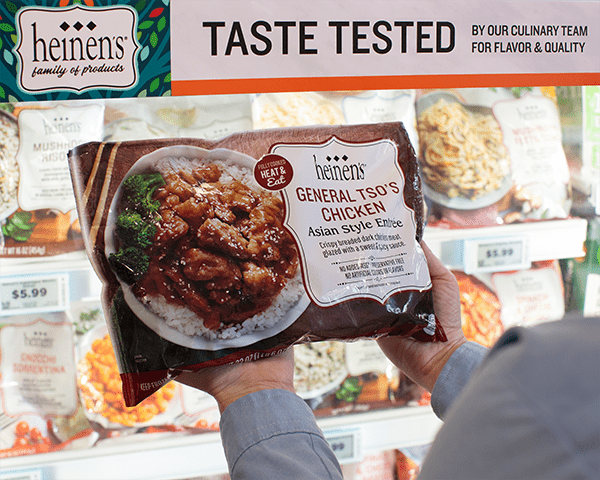 Heinen's Private Label General Tso's Chicken being held by an asoociate