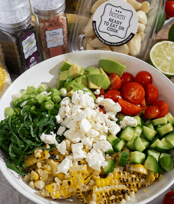 Avocado & Corn Salad unmixed in a bowl surrounded by its ingredients