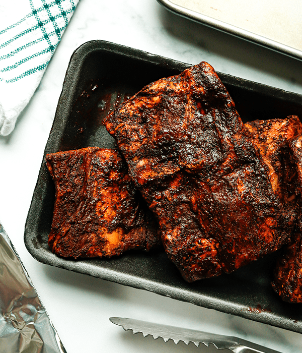 Campfire Coffee-Crusted Beef Ribs right off the grill and sitting on the kitchen counter with prongs