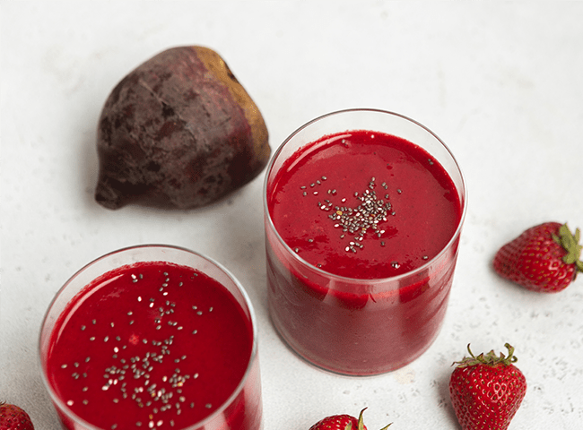 Strawberry Vanilla Beet Smoothie in a glass surrounded by raw ingredients