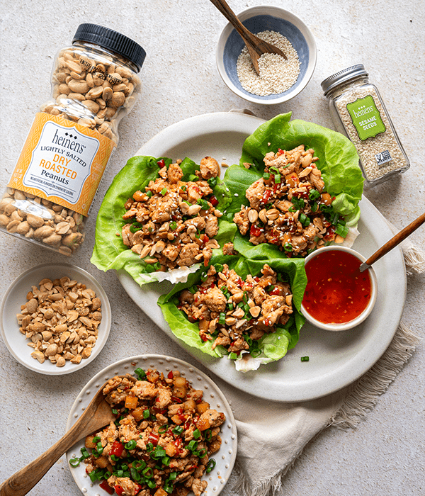 The Chicken Lettuce Wraps plated on a white plate surrounded by nuts and seeds