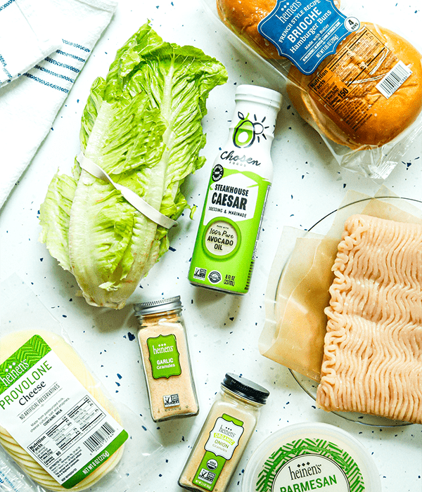 the ingredients laid out on a white table for the Chicken Caesar Smash Burger