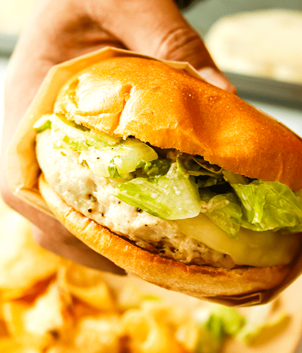 a handing holding the freshly prepared Chicken Caesar Smash Burger